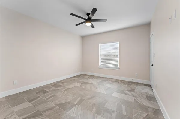 an empty room with a ceiling fan and window