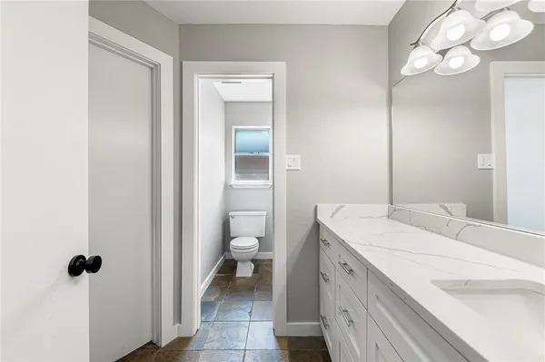 a spacious bathroom with a sink a toilet and a mirror