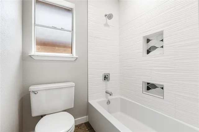 a white toilet sitting next to a bath tub