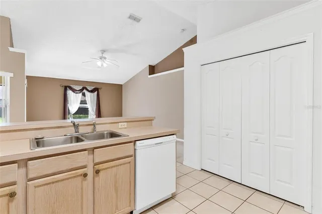 an empty room with a chandelier fan and windows