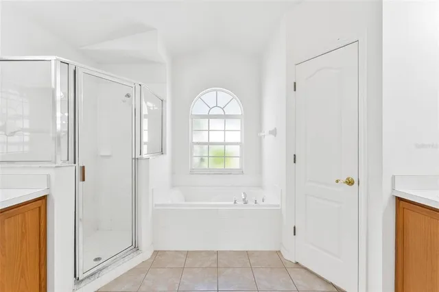 a bathroom with a granite countertop sink a mirror a bathtub and next to a window