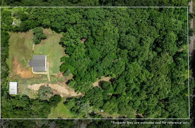 an aerial view of a residential houses with outdoor space and trees
