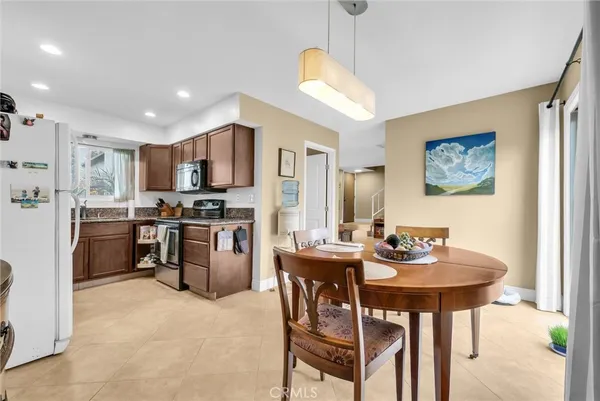 a kitchen with a refrigerator a stove a sink dishwasher with a dining table and chairs