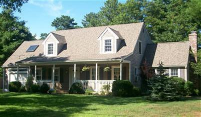 a view of a white house next to a yard with plants and trees