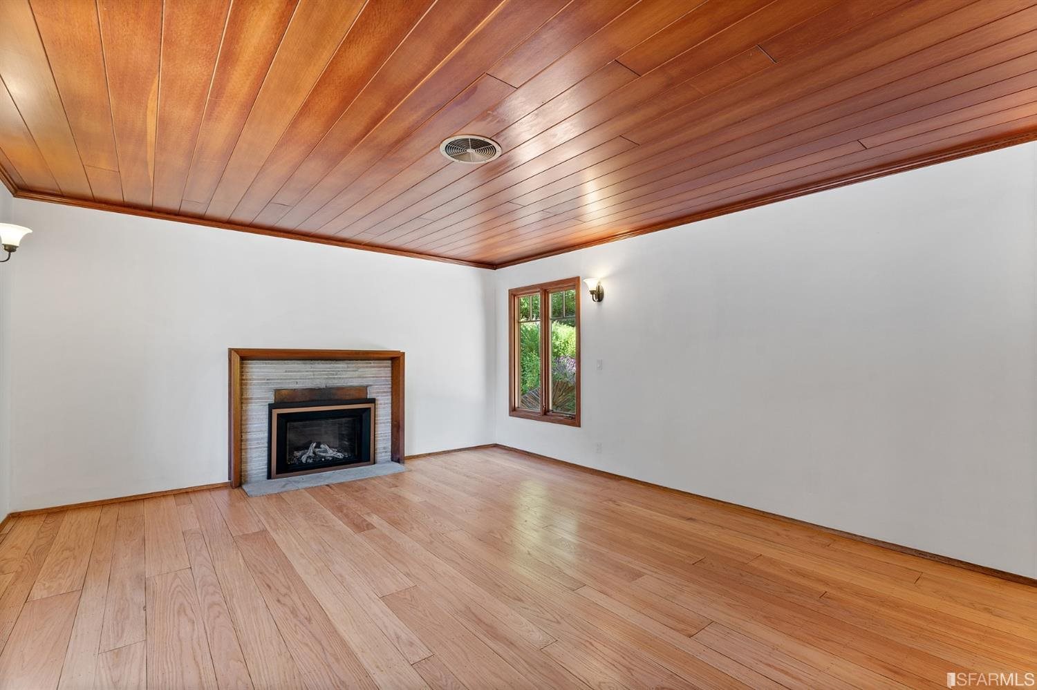 1180 Park Hills Road Berkeley, CA 94708 - Photo 15 of 62 a view of an empty room with wooden floor fireplace and a window