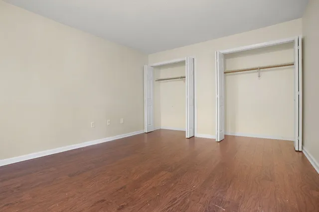 a view of an empty room with wooden floor and closet