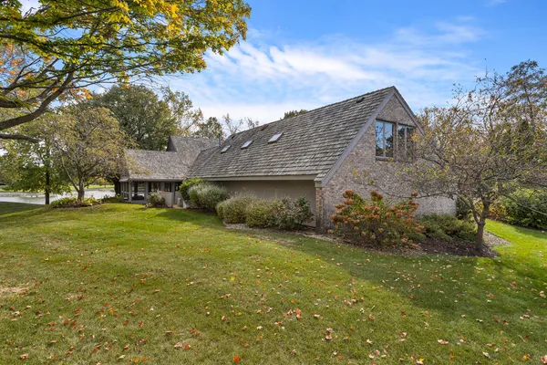 a brick house next to a yard with big trees