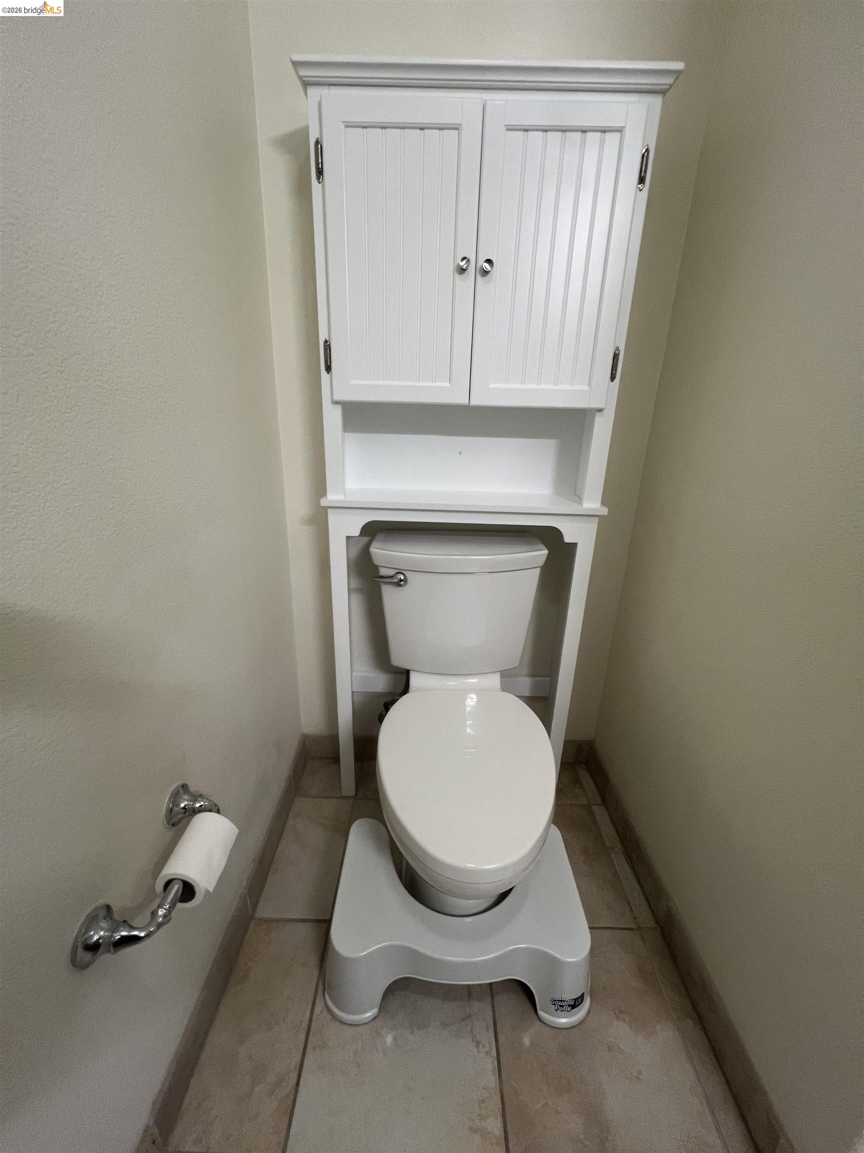 423 7th Street, Unit 313 Oakland, CA 94607 - Photo 11 of 11 Bathroom featuring tile flooring and an over-the-toilet storage cabinet with beadboard cabinet doors and chrome hardware