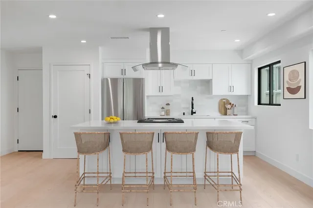 a kitchen with stainless steel appliances a table chairs refrigerator and cabinets