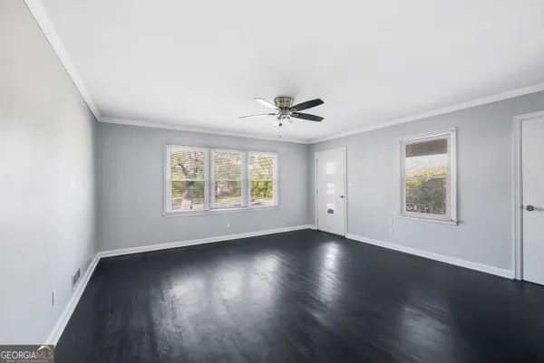 an empty room with wooden floor and windows