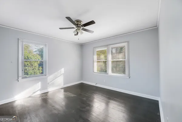 a view of empty room with wooden floor and fan