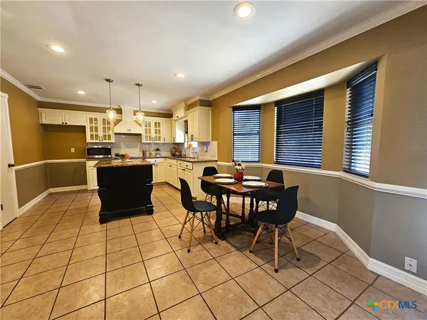 a room with stainless steel appliances kitchen island granite countertop a sink and cabinets