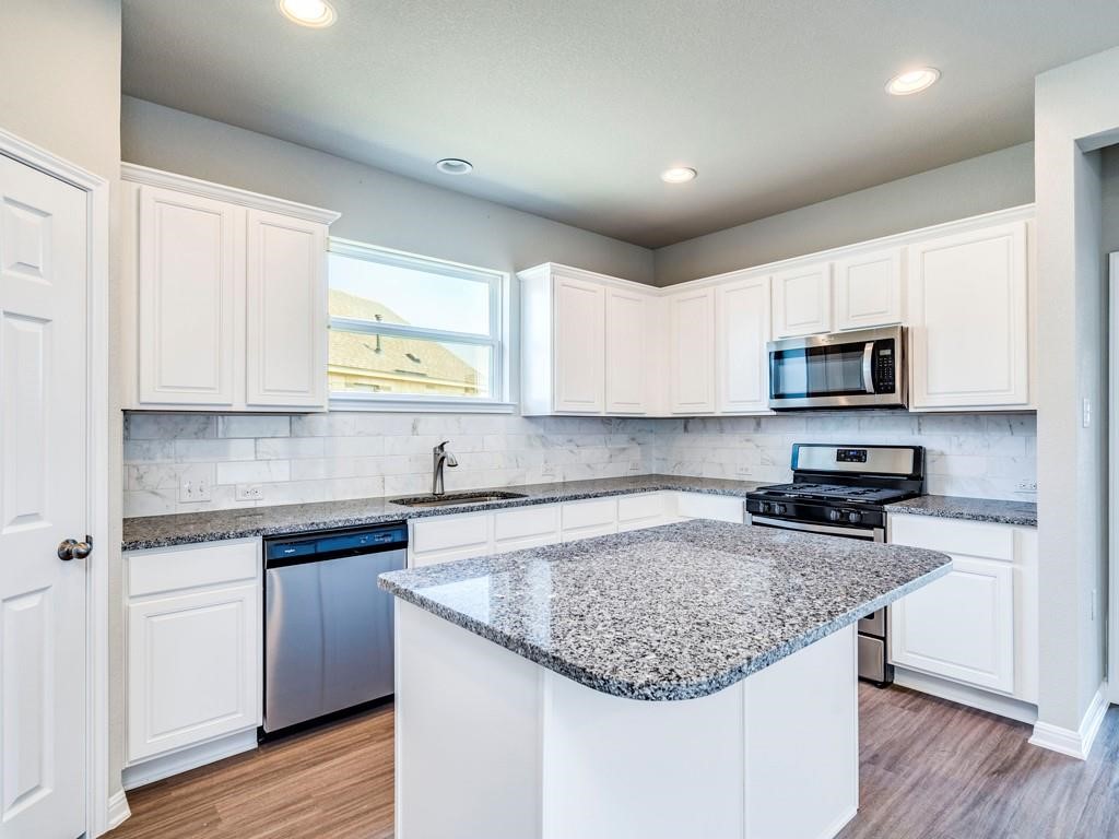 4210 Birdwatch Loop, Unit 2 Pflugerville, TX 78660 - Photo 11 of 31 A well-appointed kitchen features white cabinetry, granite countertops, and modern stainless steel appliances.