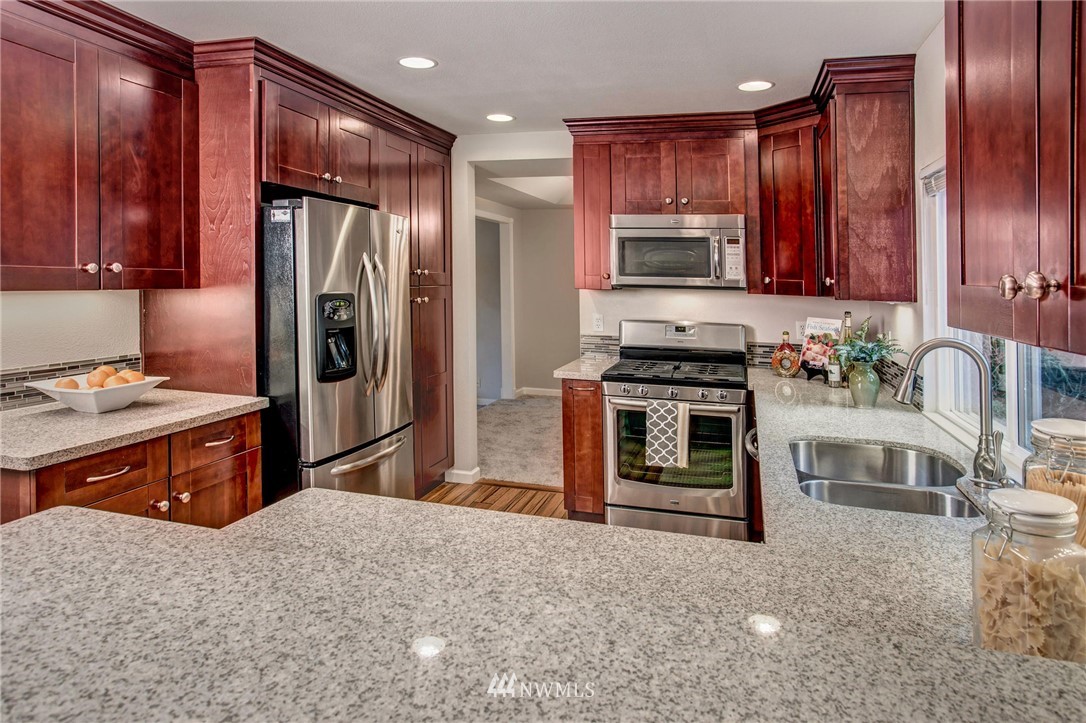 23613 Meridian Place West Bothell, WA 98021 - Photo 12 of 32 a kitchen with stainless steel appliances granite countertop wooden cabinets a stove top oven a sink and dishwasher