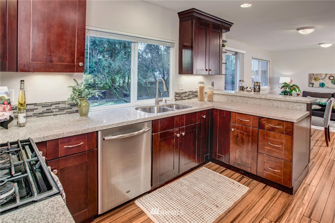 23613 Meridian Place West Bothell, WA 98021 - Photo 13 of 32 a kitchen with stainless steel appliances granite countertop wooden cabinets a sink and dishwasher a stove with wooden floor