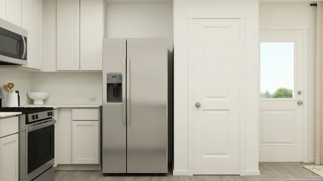 a kitchen with stainless steel appliances white cabinets and a refrigerator