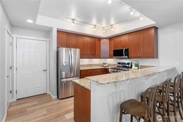 a kitchen with stainless steel appliances granite countertop a refrigerator a stove a sink a dining table and chairs with wooden floor