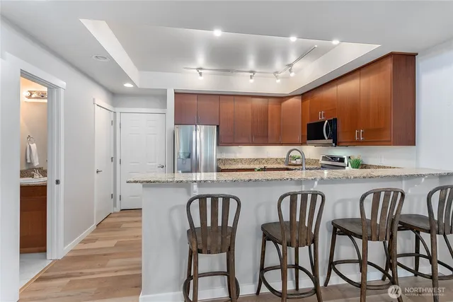 a kitchen with granite countertop a table chairs stove microwave and cabinets