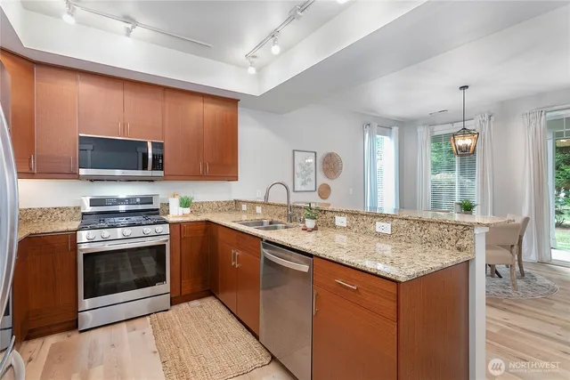 a kitchen with stainless steel appliances granite countertop a stove top oven a sink and a microwave