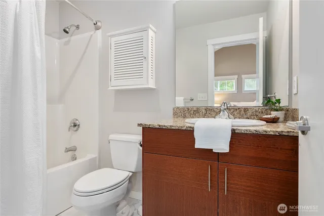 a bathroom with a granite countertop sink toilet and mirror