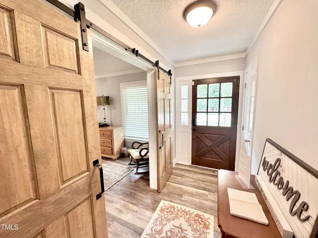 a view of a hallway with wooden floor and a bedroom