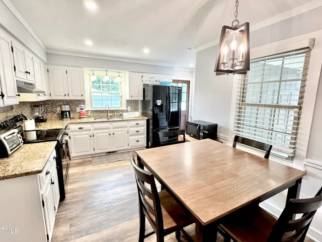 a kitchen with stainless steel appliances kitchen island granite countertop a stove a sink dishwasher and white cabinets with wooden floor