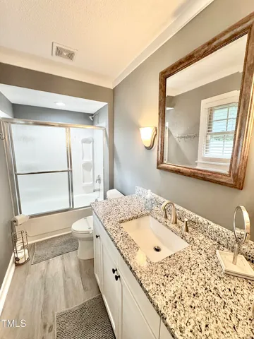 a bathroom with a granite countertop sink toilet and shower