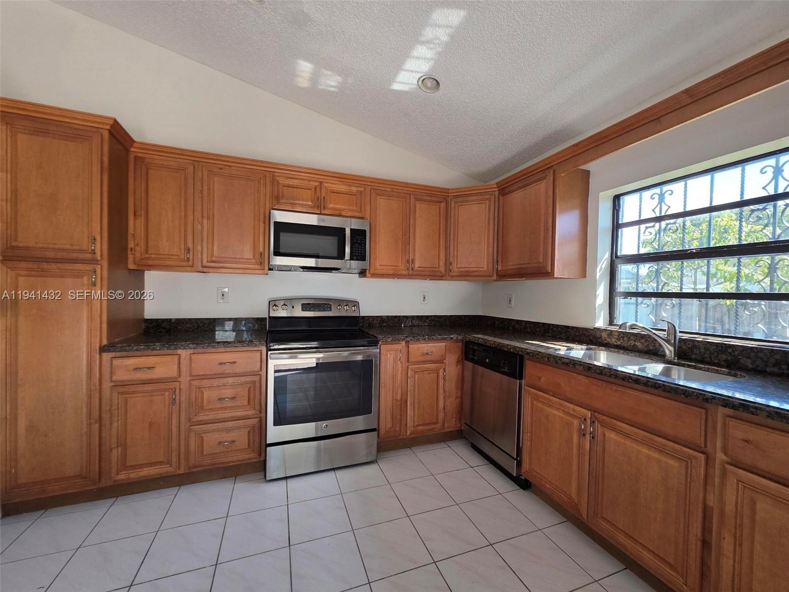 15238 Southwest 58th Terrace Miami, FL 33193 - Photo 11 of 38 a kitchen with granite countertop a stove top oven microwave and cabinets
