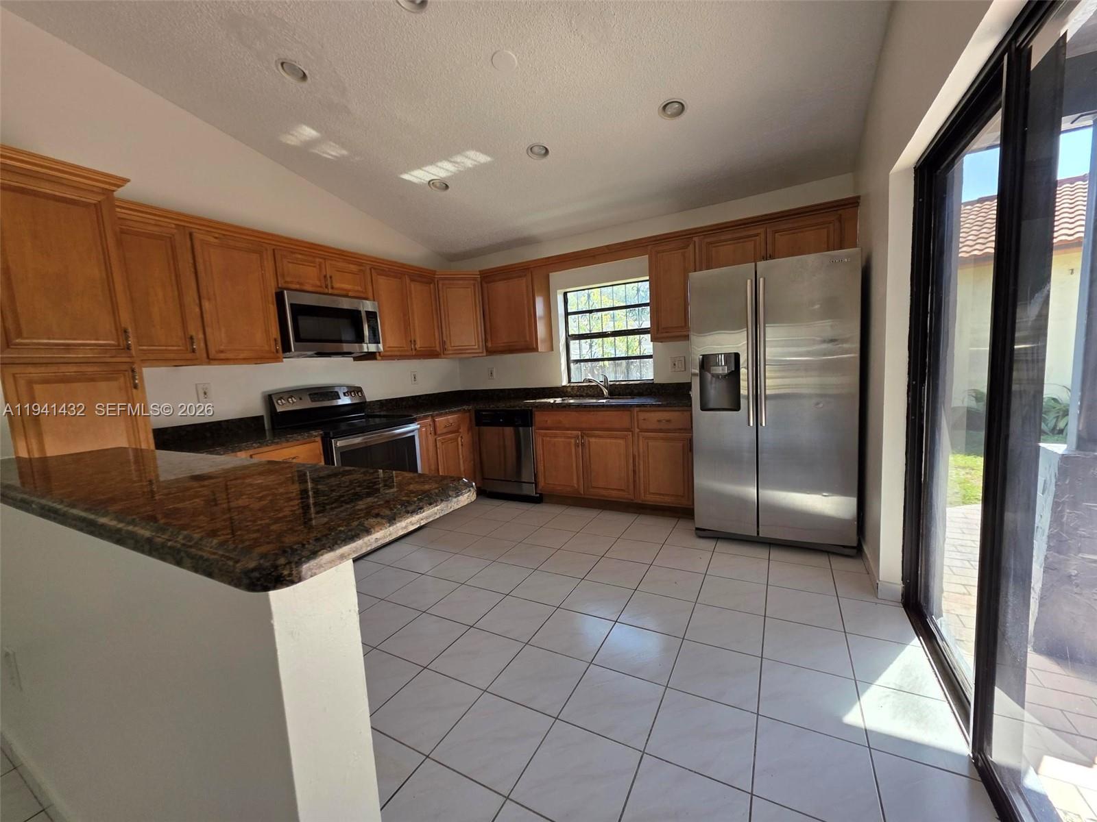 15238 Southwest 58th Terrace Miami, FL 33193 - Photo 13 of 38 a kitchen with stainless steel appliances granite countertop a refrigerator a stove a sink a microwave and a dining table with wooden cabinet