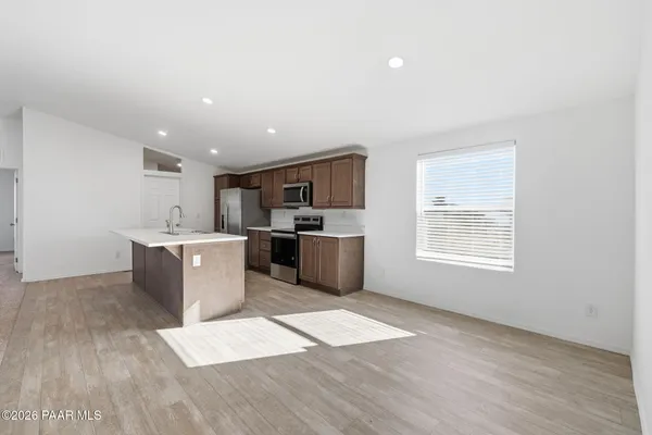 a kitchen with stainless steel appliances granite countertop a sink a stove top oven and a wooden floor