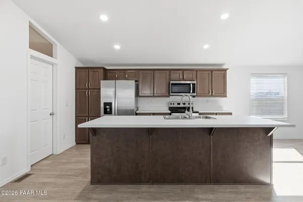 a large kitchen with kitchen island a sink a stove a refrigerator cabinets and a window