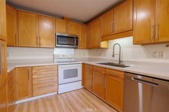 a kitchen with granite countertop wooden cabinets stainless steel appliances and a sink