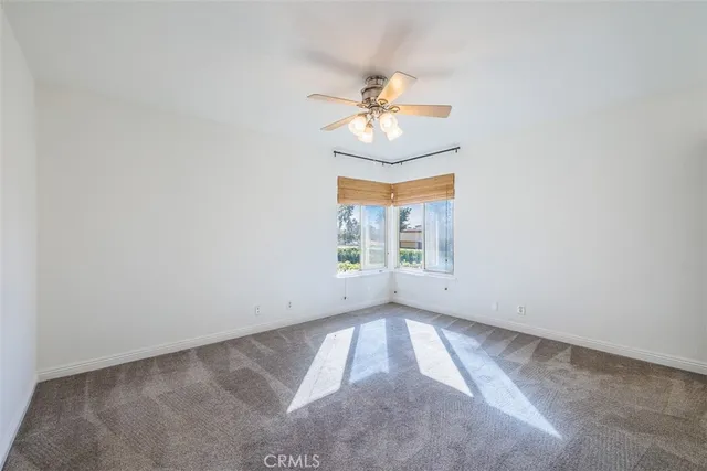 an empty room with chandelier fan and windows
