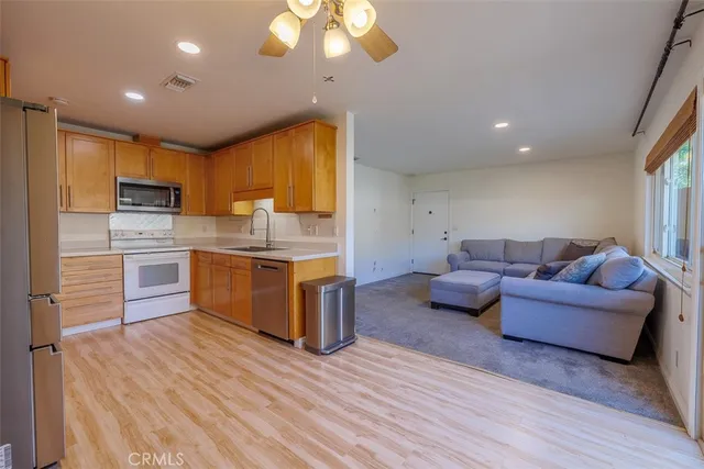 a kitchen with stainless steel appliances granite countertop a stove top oven a sink dishwasher and white cabinets with wooden floor