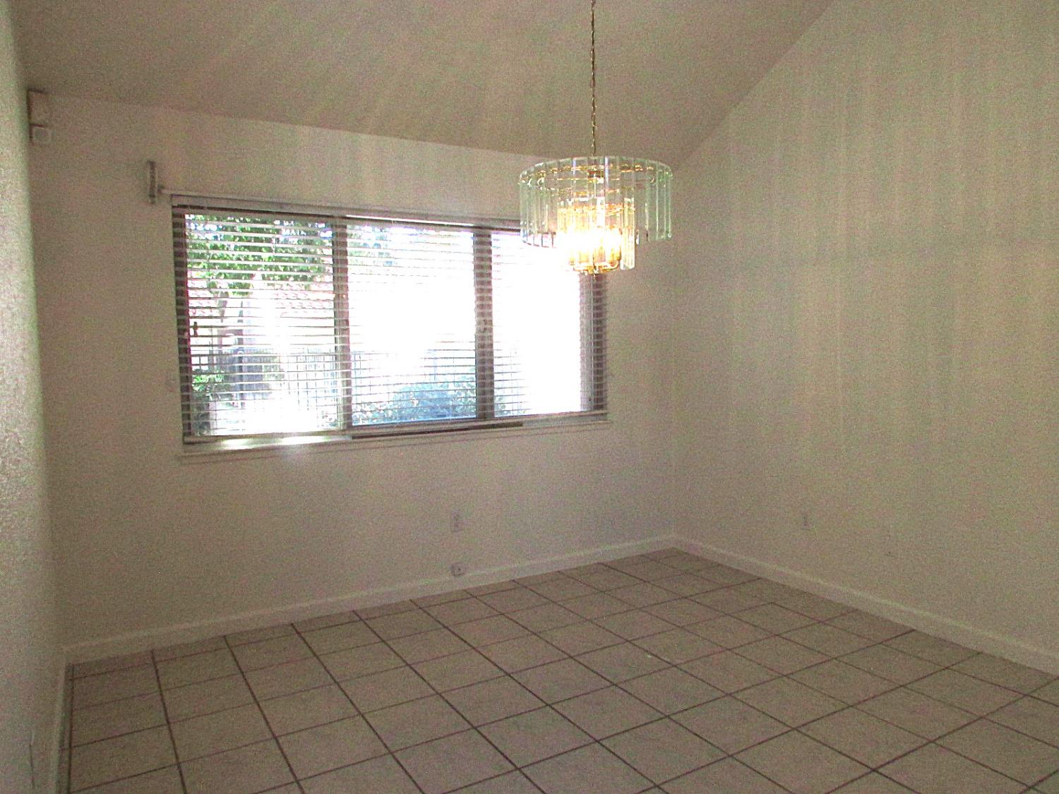 1855 Scenic Drive, Unit F Modesto, CA 95355 - Photo 23 of 52 an empty room with chandelier fan and windows