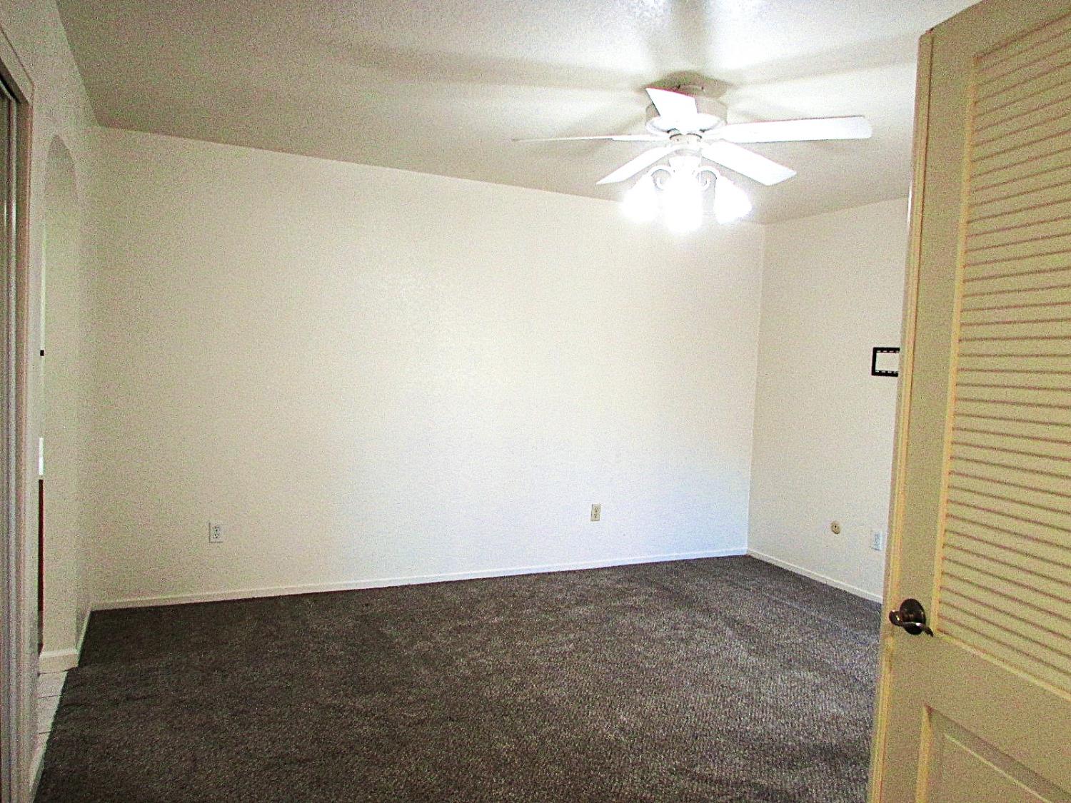1855 Scenic Drive, Unit F Modesto, CA 95355 - Photo 38 of 52 an empty room with a ceiling fan and a window