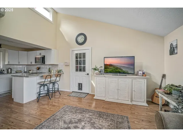 a living room with a flat screen tv and kitchen view