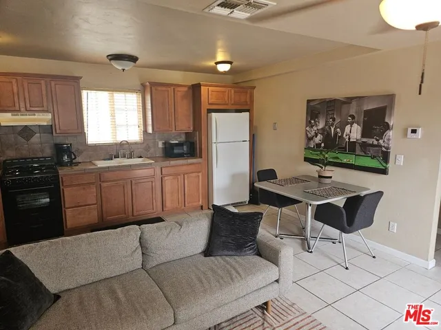 a kitchen with stainless steel appliances granite countertop a sink a stove a refrigerator dining table and chairs