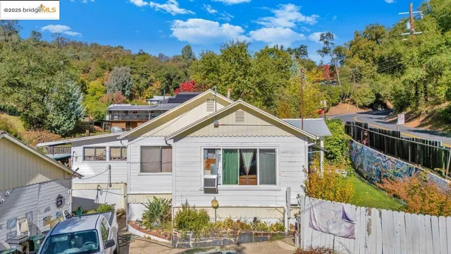 a view of a white house with a small yard and wooden fence
