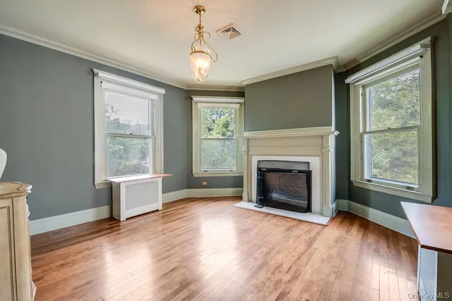 a view of a livingroom with wooden floor a fireplace and windows