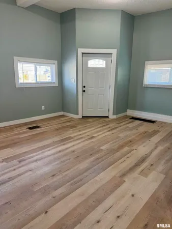 a view of an empty room with window and wooden floor