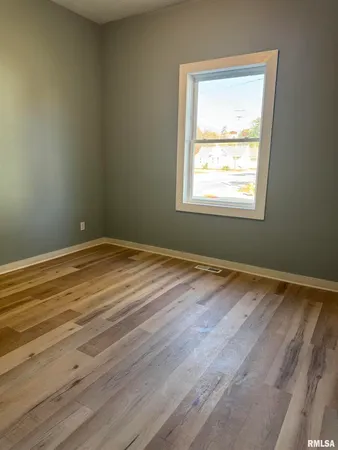 an empty room with wooden floor and a window