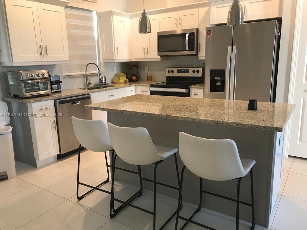 490 37th Avenue Northwest Naples, FL 34120 - Photo 7 of 16 a kitchen with stainless steel appliances granite countertop a table chairs microwave and sink