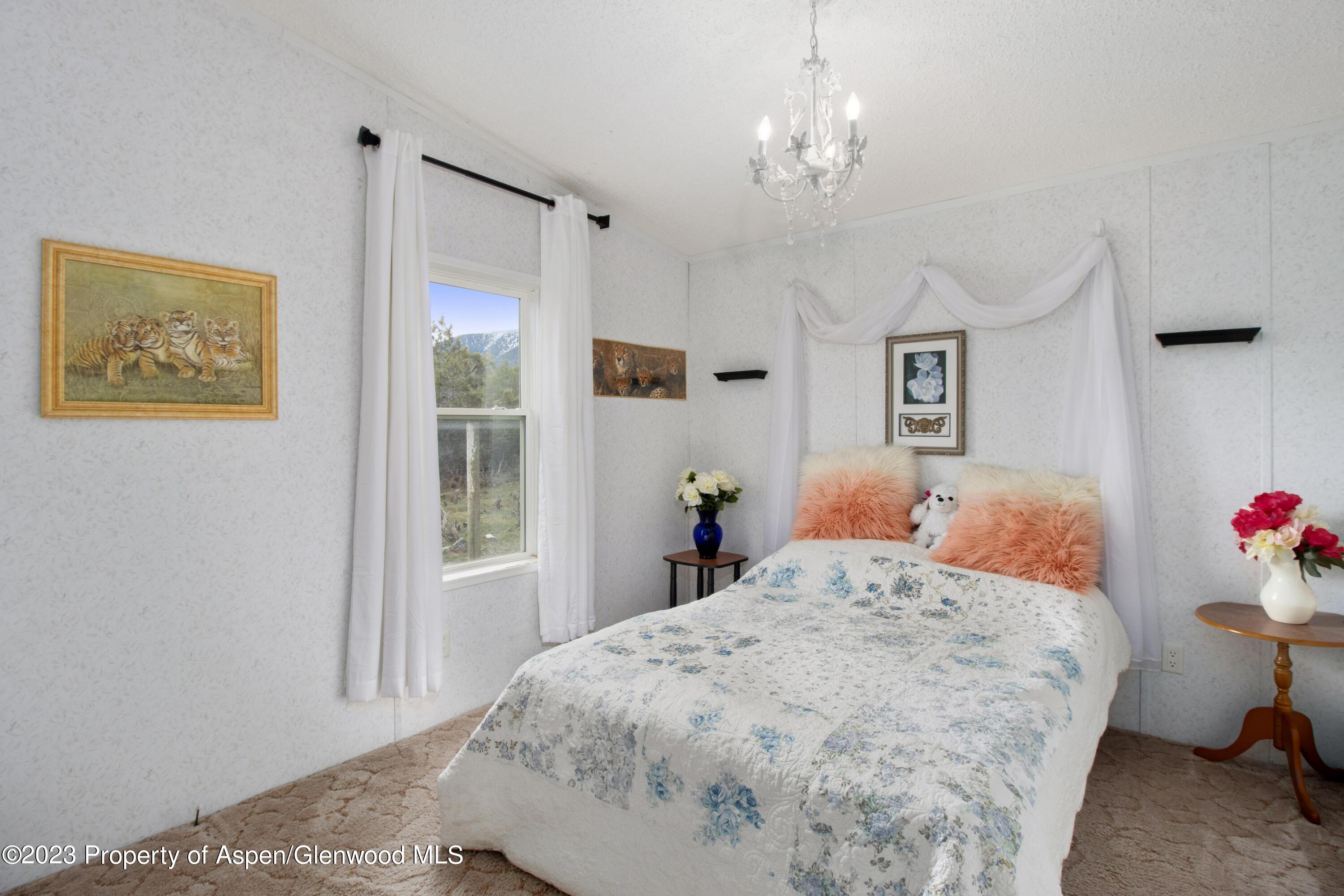 2345 County Road 306 Parachute, CO 81635 - Photo 11 of 29 a bedroom with a large bed and a chandelier