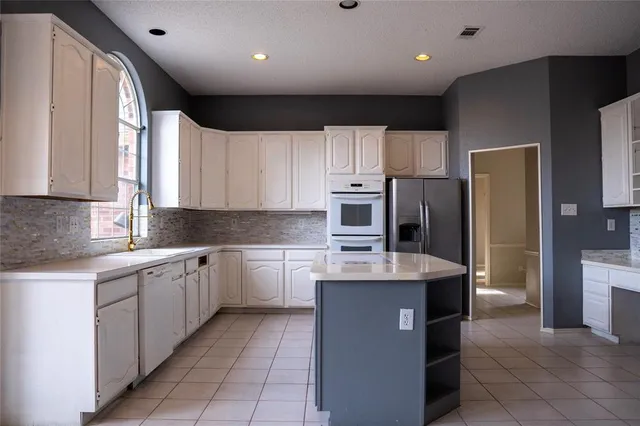 a kitchen with stainless steel appliances granite countertop a refrigerator a sink a stove a microwave and island