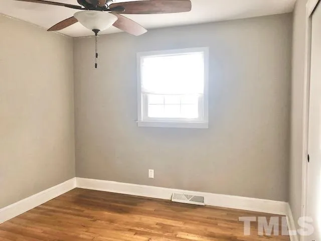 an empty room with a window and a ceiling fan