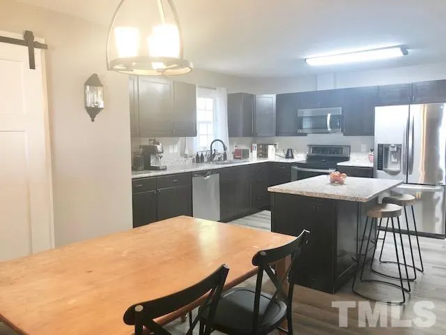 a kitchen with a dining table chairs and refrigerator
