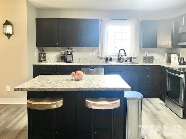 a kitchen with granite countertop kitchen island stainless steel appliances a sink and cabinets