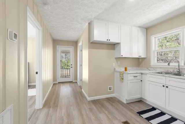 a kitchen with granite countertop a stove a sink and white cabinets with wooden floor