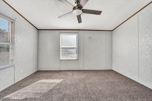 an empty room with a ceiling fan and a window
